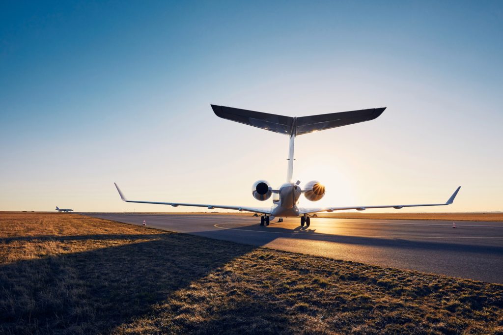 Airport at sunset. Silhouette of private jet against runway.
